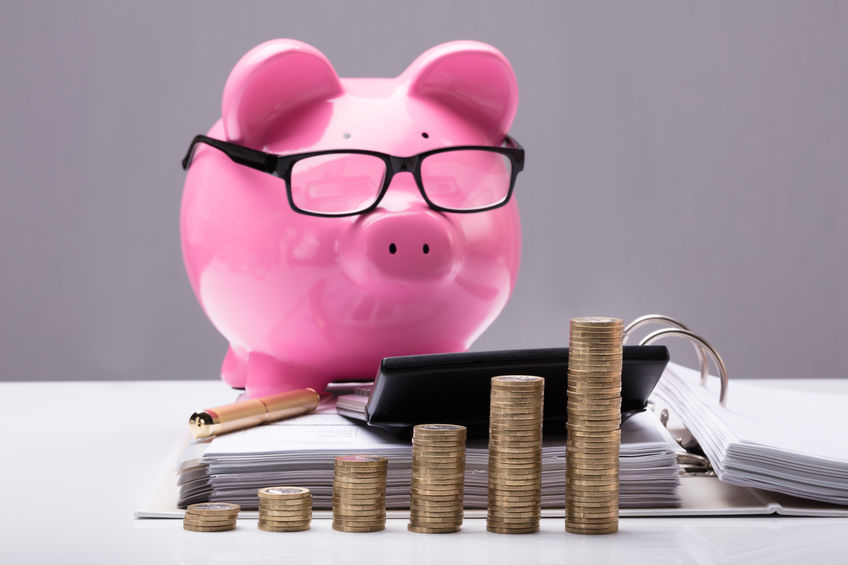 Stacked Coins And Document In Front Of Piggy Bank